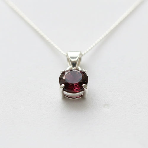 Astral Garnet Round Necklace - Sterling Silver, close-up top-down view of the sterling silver necklace with round garnet pendant on a white background.