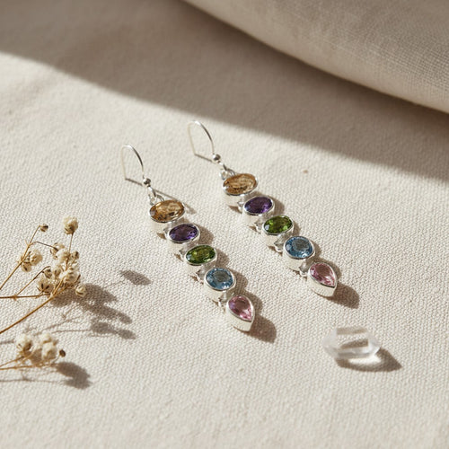Aurora Multi Gemstone Drop Earrings - Sterling Silver, multicoloured gemstone earrings on a beige fabric background with dried flowers.