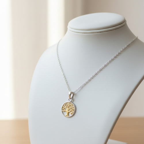 Auryn Tree of Life Necklace - Sterling Silver & Gold Plate, a silver chain necklace with a gold tree-of-life pendant displayed on a white jewelry bust against a soft beige background.