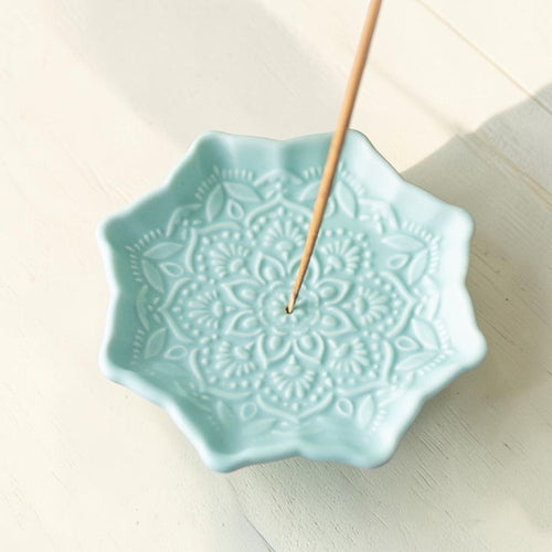 Blue Mandala Incense Stick Holder, ceramic dish with mandala textured design and an incense stick, viewed from above on a light wooden surface.
